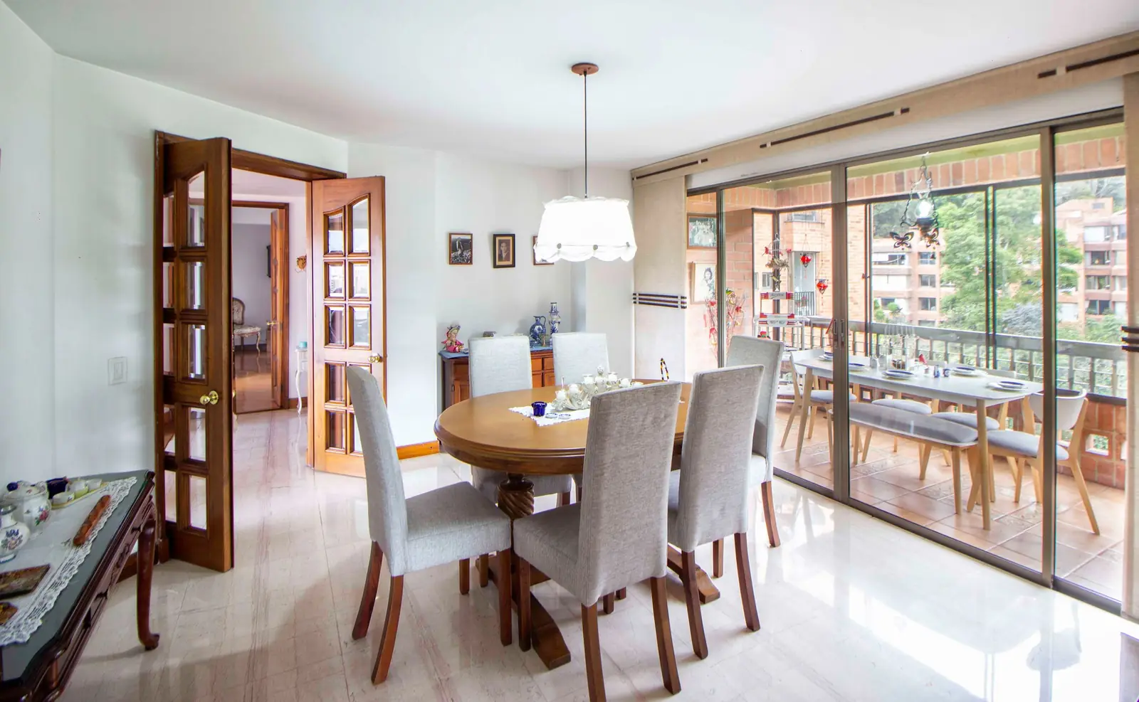 Spacious dining area with a round table, elegant chairs, and large glass doors leading to a balcony.