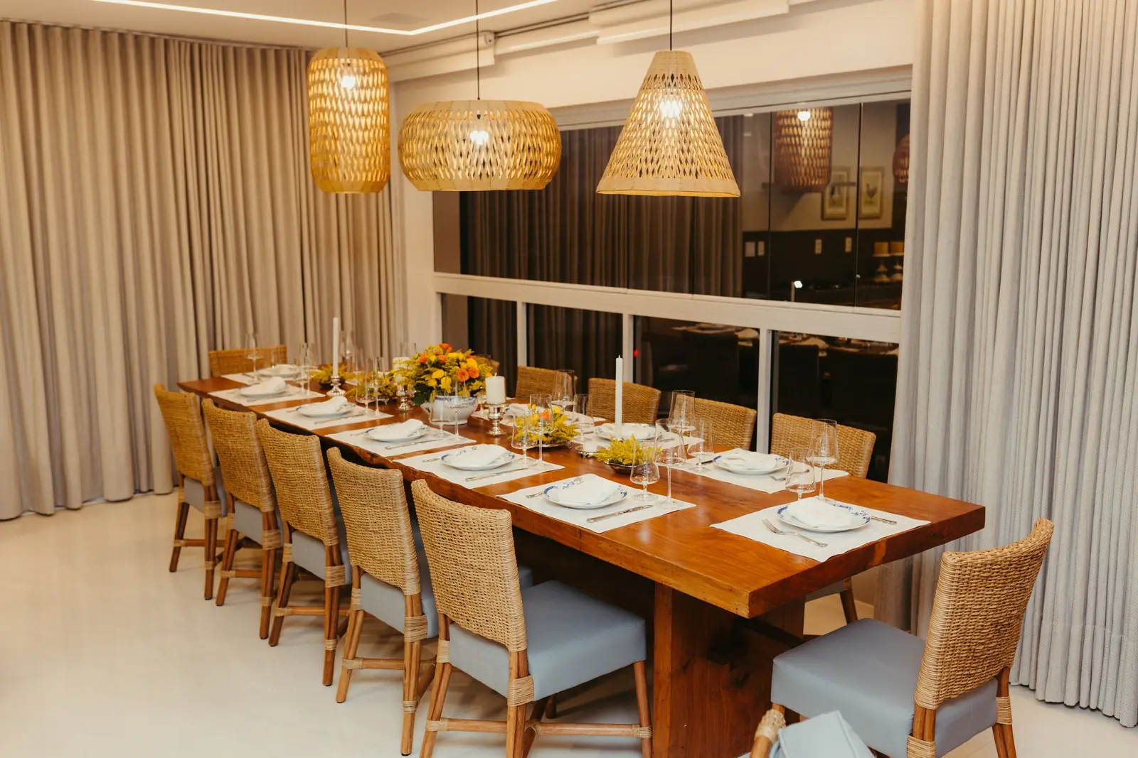 Stylish dining room with wicker chairs and pendant lights, ready for a dinner party.