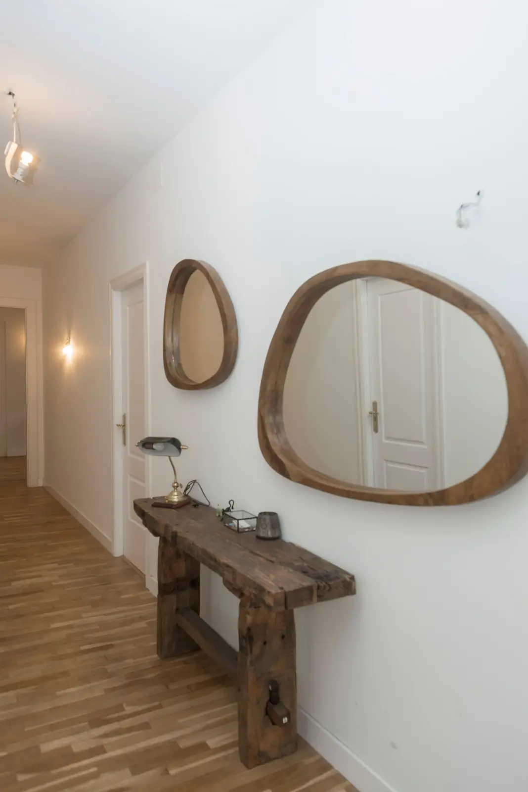 Stylish hallway with wooden mirrors and console table on white walls.