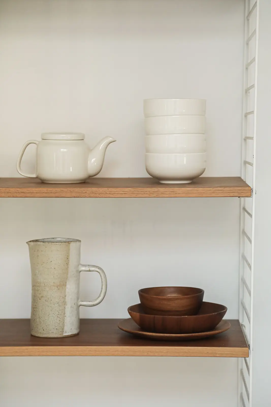 Stylish wooden shelves featuring a teapot, pitcher, and ceramic bowls.