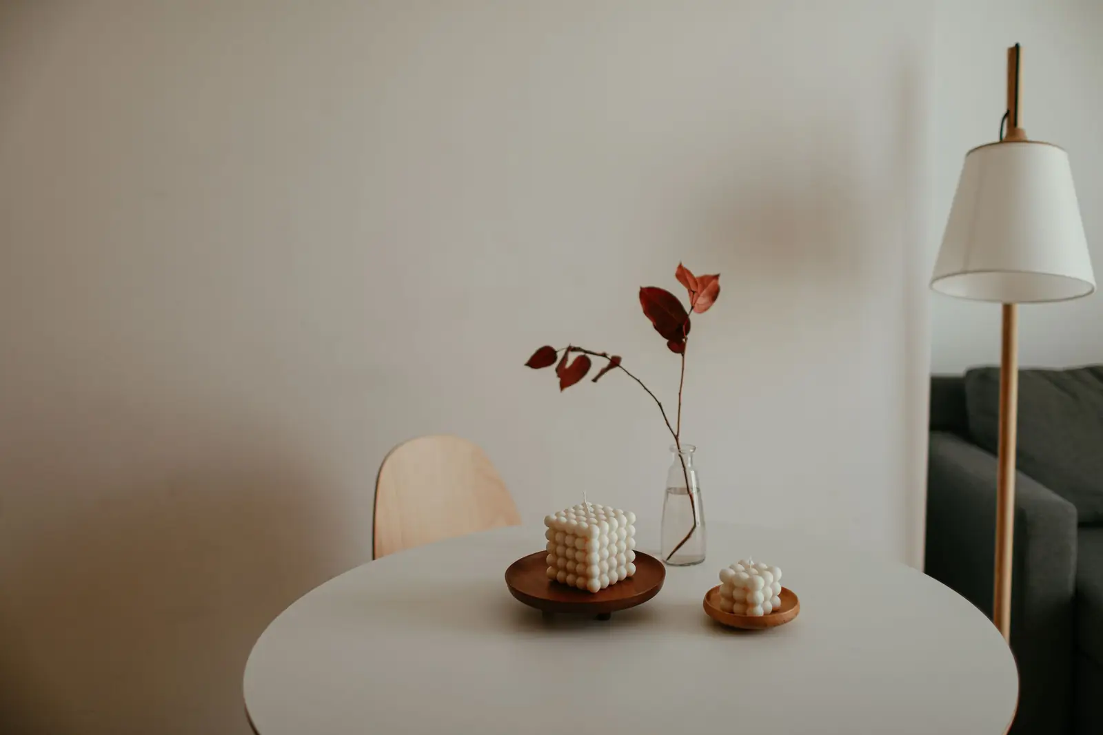 A minimalist interior with decorative candles on a table and a lamp in the background, perfect for cozy home inspiration.